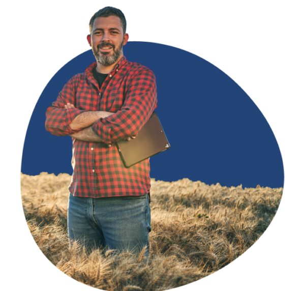 Man wearing red checkered flannel shirt, standing in a farm field.
